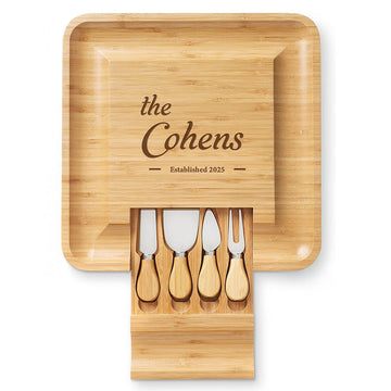 Square bamboo charcuterie board personalized for the Cohens, shown with its pull-out drawer and four serving utensils.