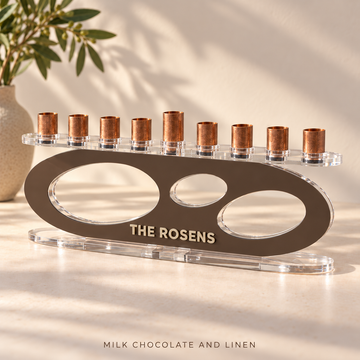 Forma acrylic menorah in Milk Chocolate and Linen personalized with THE ROSENS, with three oval openings, clear base and copper candle cups