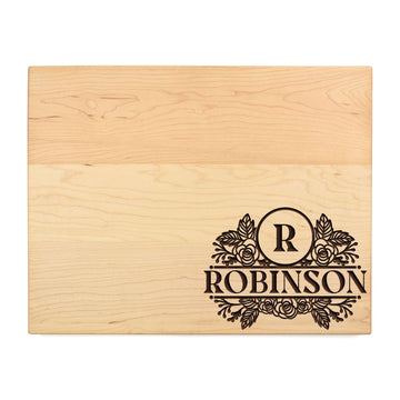 Rectangular maple cutting board engraved with the Robinson surname and floral monogram on a white background.