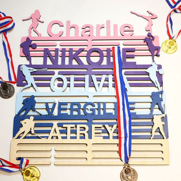 Four colorful personalized wooden medal hangers with athlete silhouettes and medals.