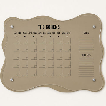 Taupe layered acrylic monthly family planner with a wavy silhouette, black calendar grid, The Cohens personalization, notes and to-do sections, and four silver wall mounts.