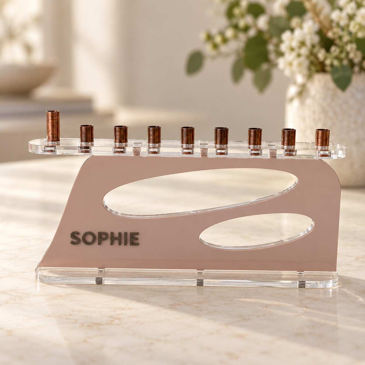 The Aperture personalized acrylic menorah in Blush and Milk Chocolate, with SOPHIE lettering, two oval openings, clear base and copper candle cups