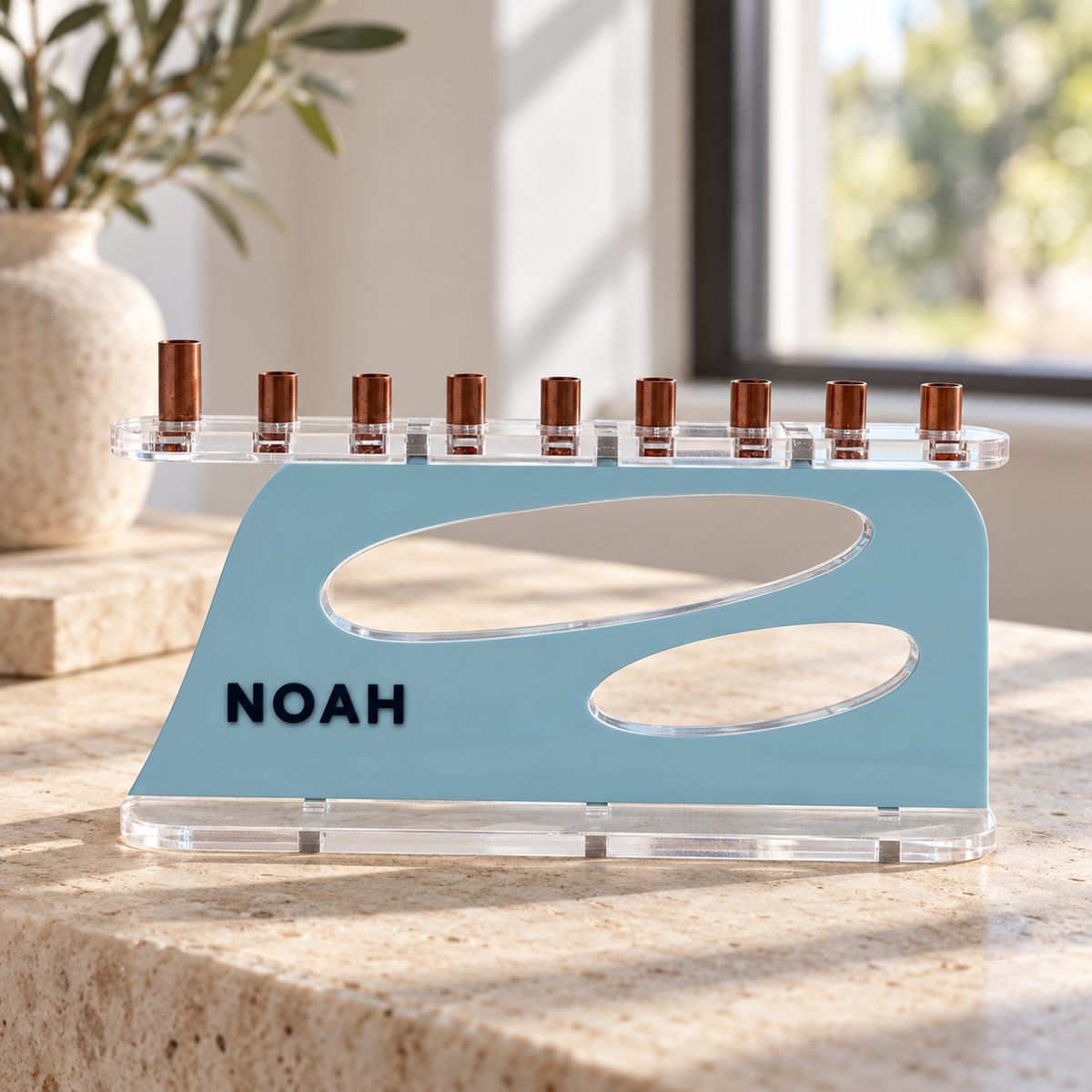 The Aperture personalized acrylic menorah in Ice and Navy, with NOAH lettering, two oval openings, clear base and copper candle cups