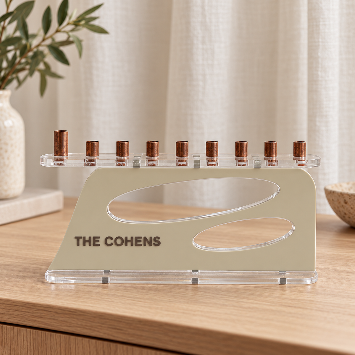 The Aperture personalized acrylic menorah in Linen and Milk Chocolate, with THE COHENS lettering, two oval openings, clear base and copper candle cups