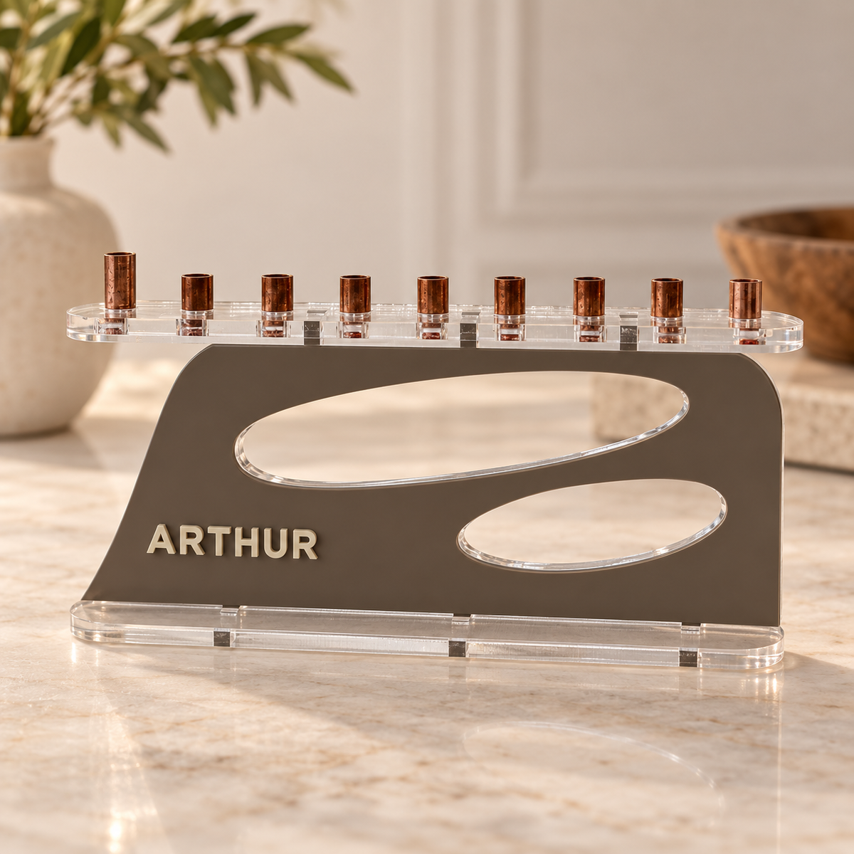 The Aperture personalized acrylic menorah in Milk Chocolate and Linen, with ARTHUR lettering, two oval openings, clear base and copper candle cups