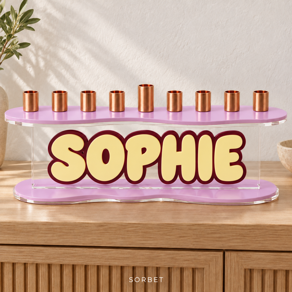 SOPHIE personalized menorah in Sorbet, with Strawberry Milk curved plates, Lemon Chiffon letters and a Wine outline on an oak console
