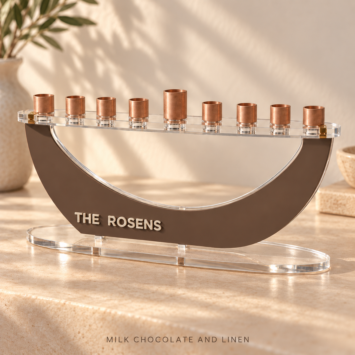 Angled view of THE ROSENS custom Crescent menorah in Milk Chocolate and Linen, showing layered acrylic lettering and a clear oval base