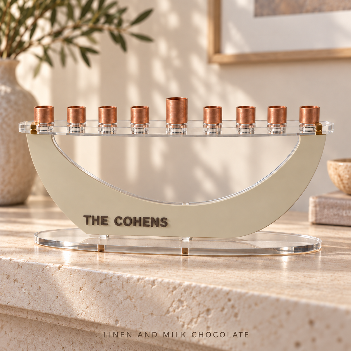 THE COHENS custom Crescent menorah in Linen and Milk Chocolate, with layered lettering and a clear acrylic top on travertine