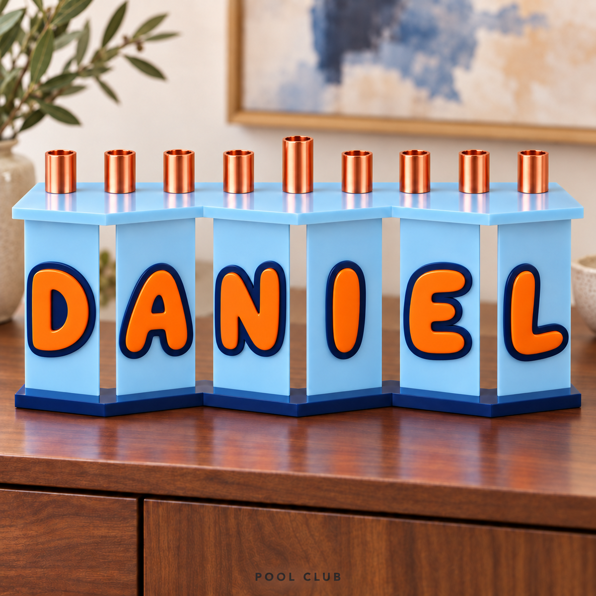 DANIEL custom acrylic menorah in Pool Club with Bluebell panels, Orange letters and Navy outlines on a wooden cabinet.