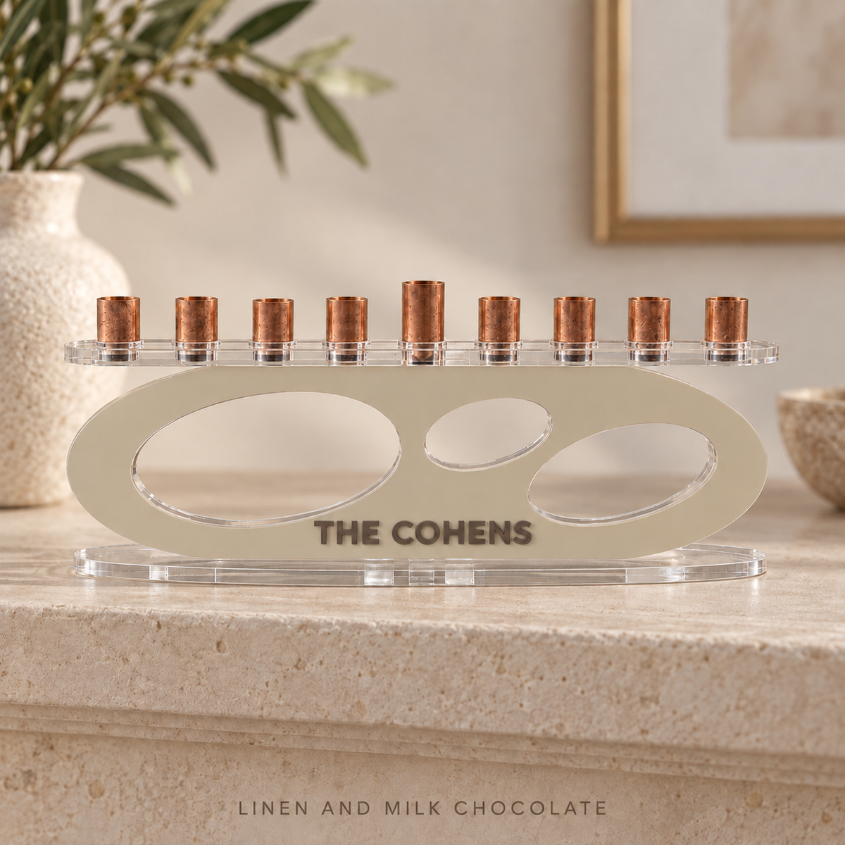 THE COHENS acrylic Forma menorah in Linen and Milk Chocolate, with layered lettering and three oval openings on travertine