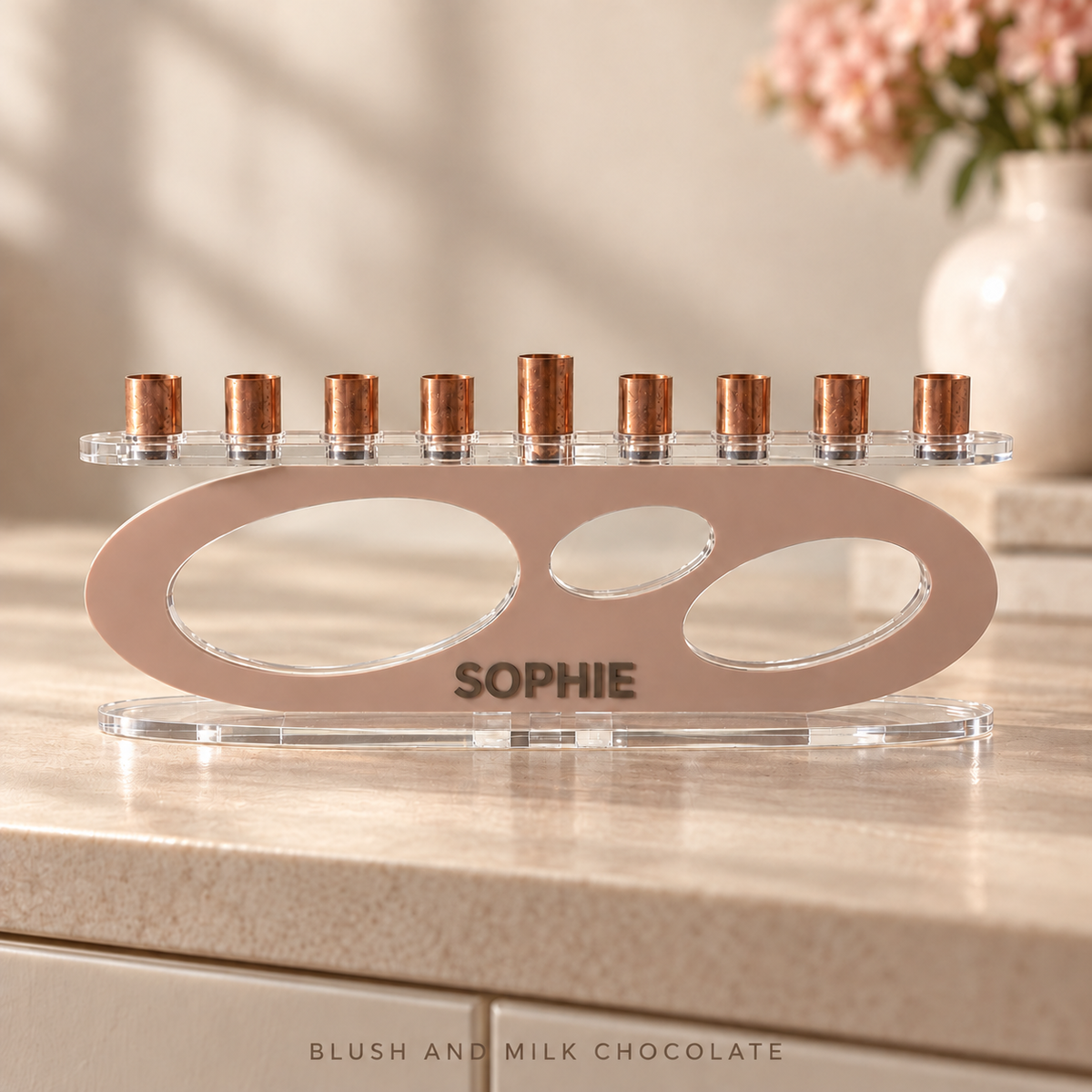 SOPHIE custom acrylic Forma menorah in Blush and Milk Chocolate, shown on a stone surface beside soft pink flowers