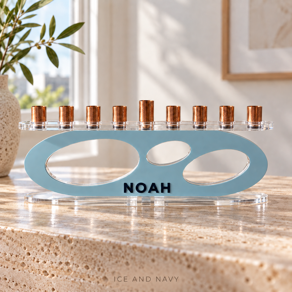 NOAH modern Forma menorah in Ice and Navy, with raised navy letters and clear acrylic base on sunlit travertine