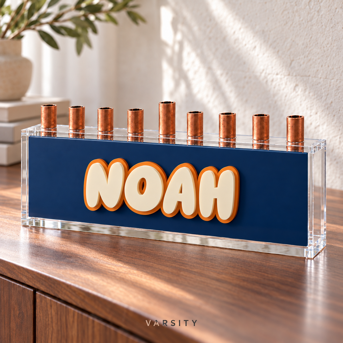 Varsity personalized menorah with raised Eggshell NOAH letters and an orange acrylic outline on a navy panel