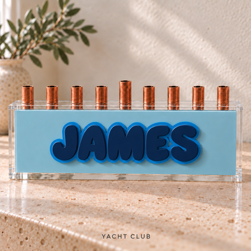 The Classic personalized acrylic menorah in Yacht Club: Ice panel, Earth Toned Navy JAMES letters, Light Blue outlines and clear box.