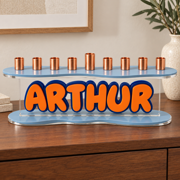 ARTHUR personalized acrylic menorah with pale blue curved plates, orange name and navy outline on a walnut console