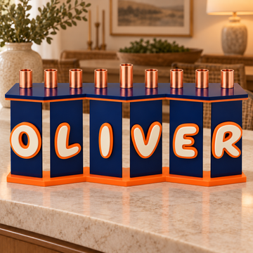 OLIVER personalized acrylic menorah with navy zigzag panels, cream letters and orange outlines on a stone console