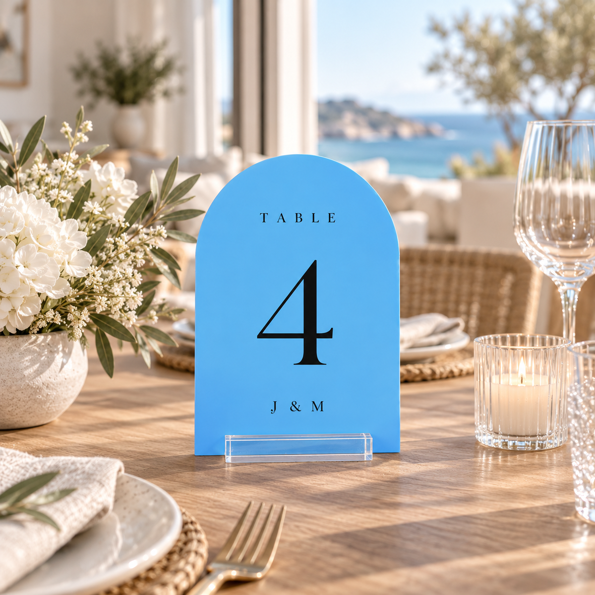 Light Blue arched acrylic wedding table number 4 with personalized initials in a clear stand on a reception table