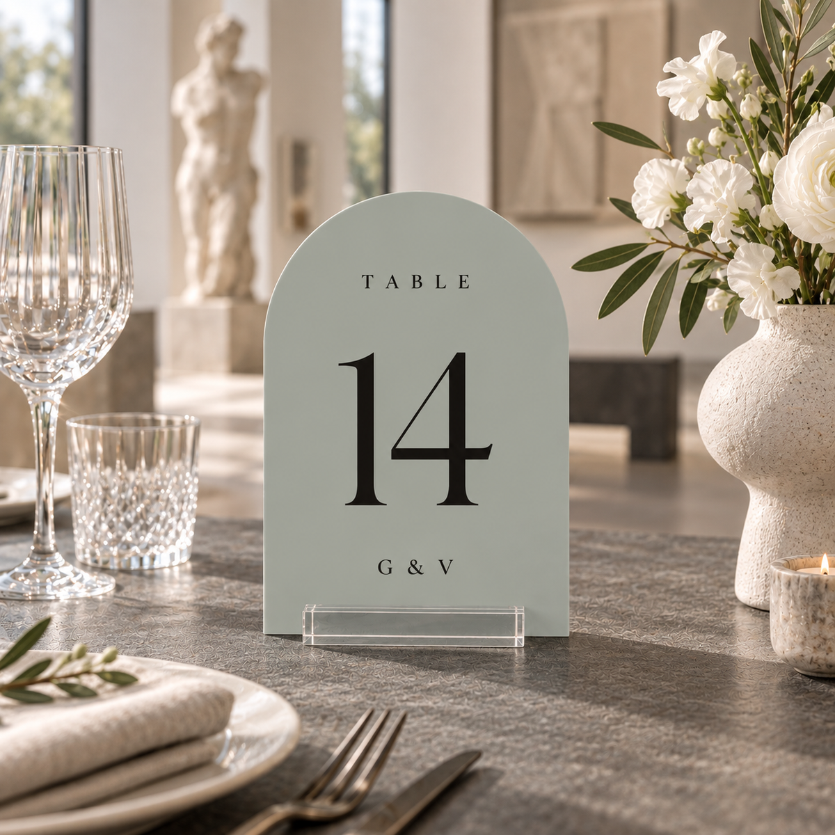 pebble arched acrylic wedding table number 14 with personalized initials in a clear stand on a reception table