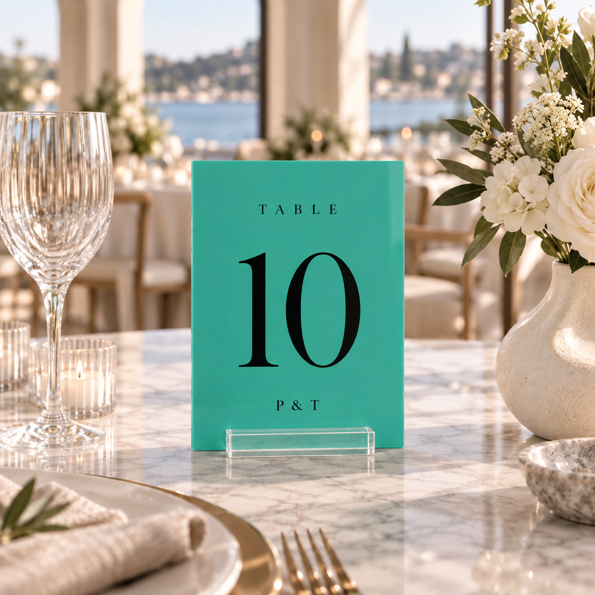 teal rectangular acrylic wedding table number 10 with personalized initials in a clear stand on a reception table