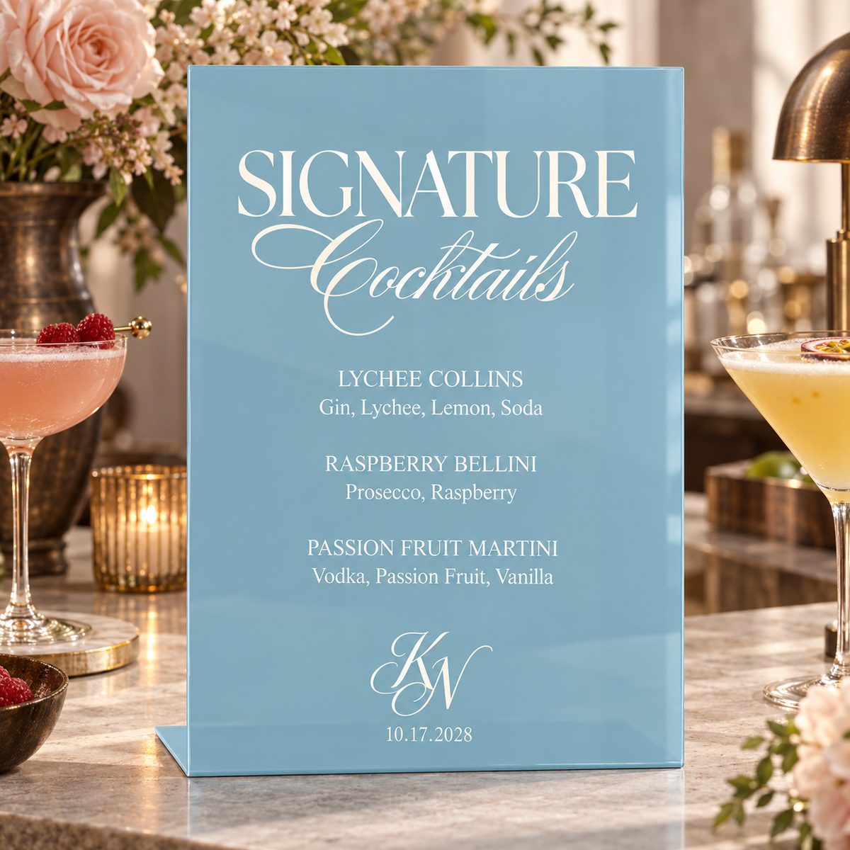 Ice acrylic signature cocktail menu on a wedding bar beside pink and white flowers