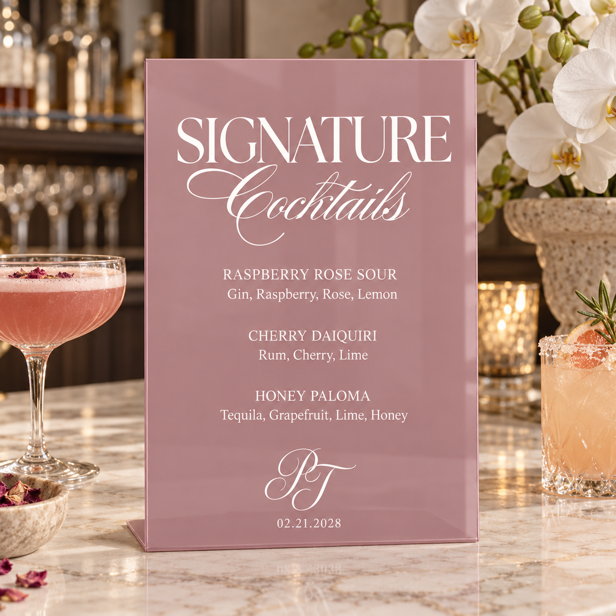Mauve Berry acrylic wedding cocktail menu with white lettering beside pink flowers