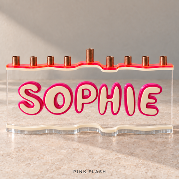 The Wave personalized SOPHIE menorah in Pink Flash, with a Neon Pink/Orange top, Eggshell letters and base, Fuchsia outlines and clear acrylic.
