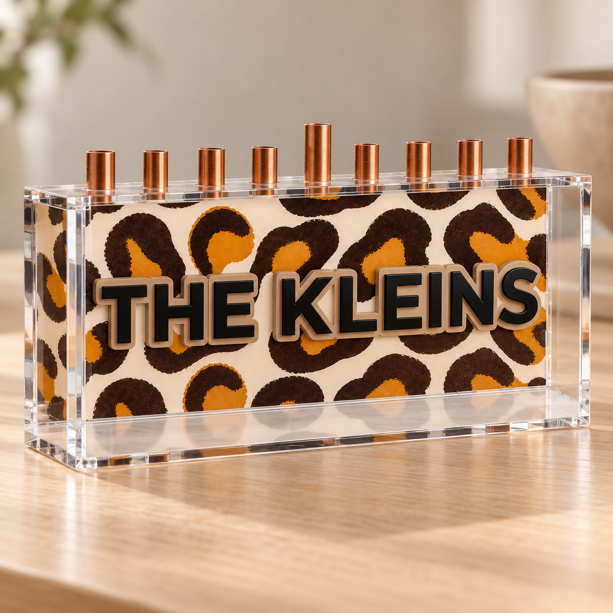 Angled view of THE KLEINS leopard print menorah with black family name and clear acrylic enclosure