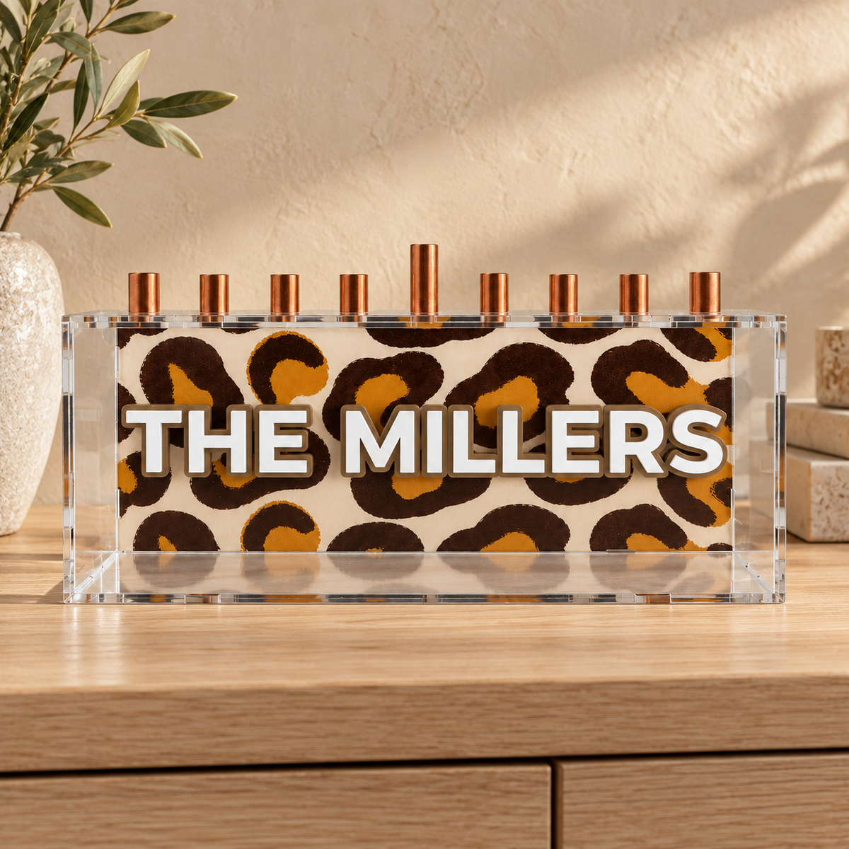 THE MILLERS personalized leopard print menorah with white lettering on an oak sideboard