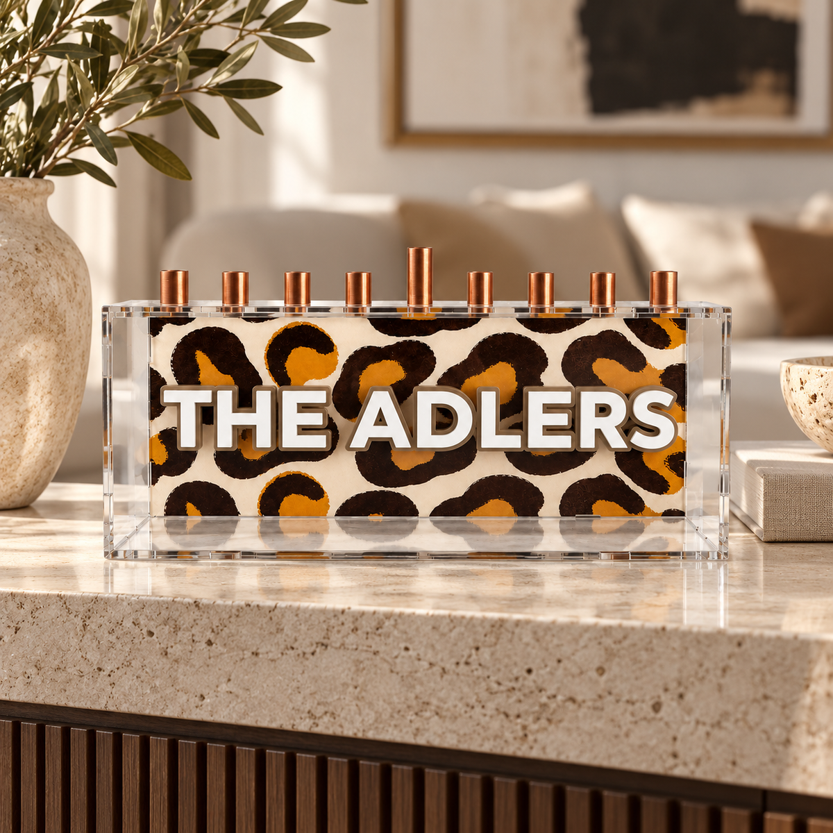 THE ADLERS personalized leopard print menorah with white letters displayed in a neutral living room